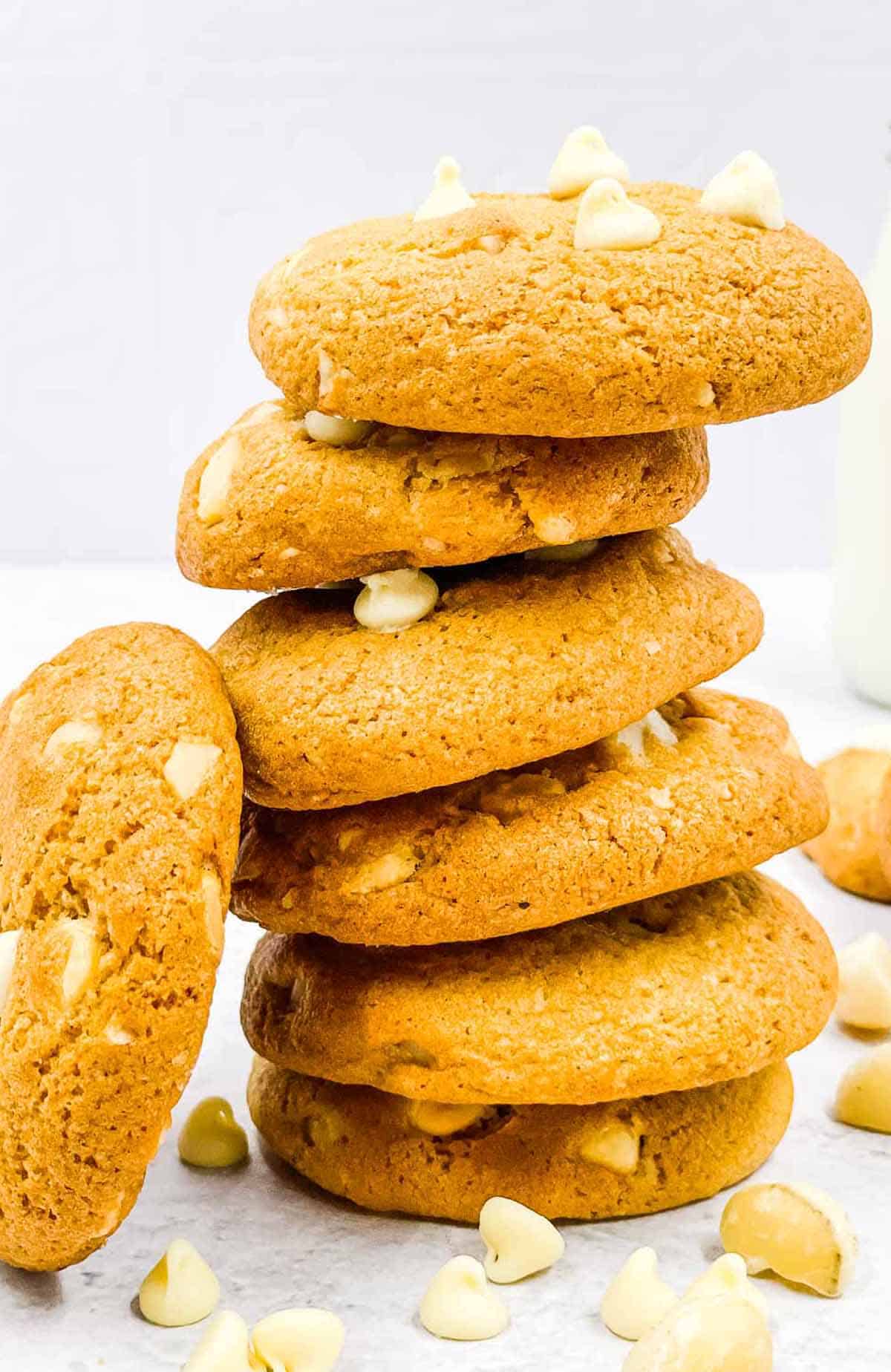 White chocolate macadamia nut cookies stacked up with one leaning on the side.
