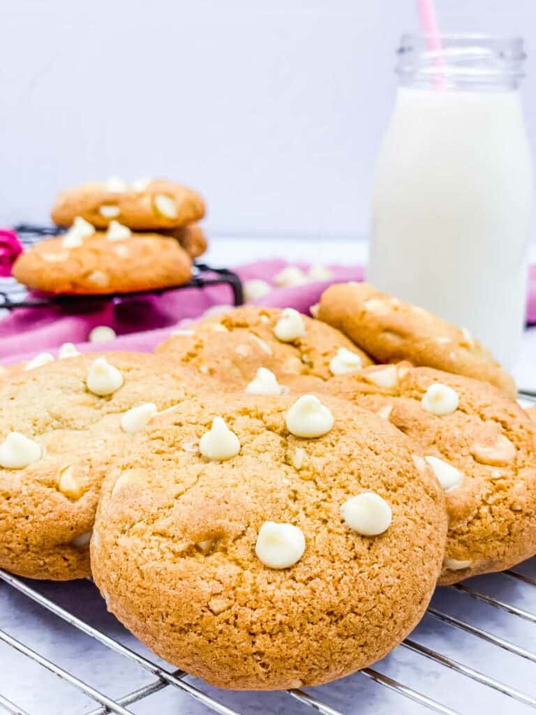 White chocolate macadamia nut cookies with a glass of milk behind.