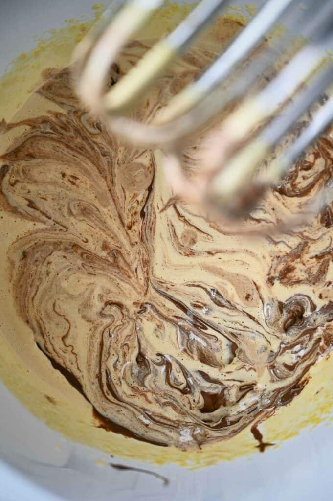 Melted chocolate added to egg yolks in stand mixer.