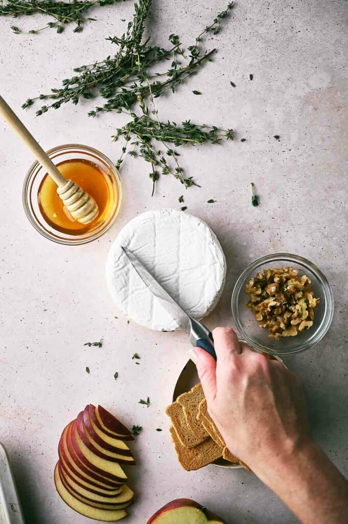 Someone scoring the top of brie rind.