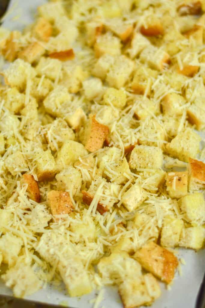Bread cubes tossed in oil and with cheese over them.