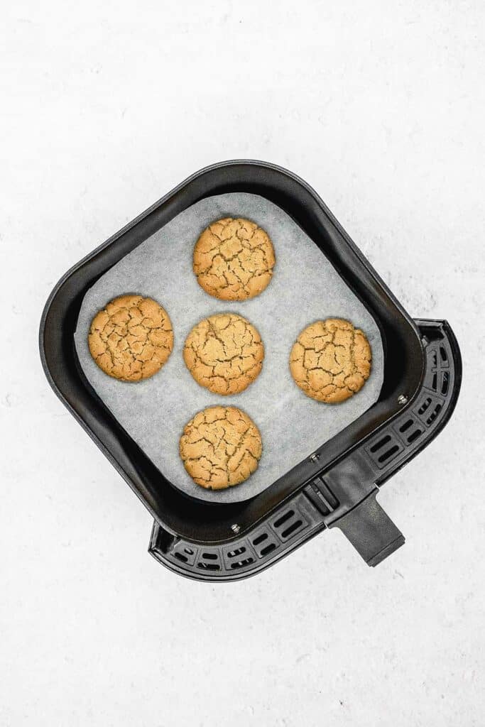 Cooked peanut butter cookies in an air fryer basket.