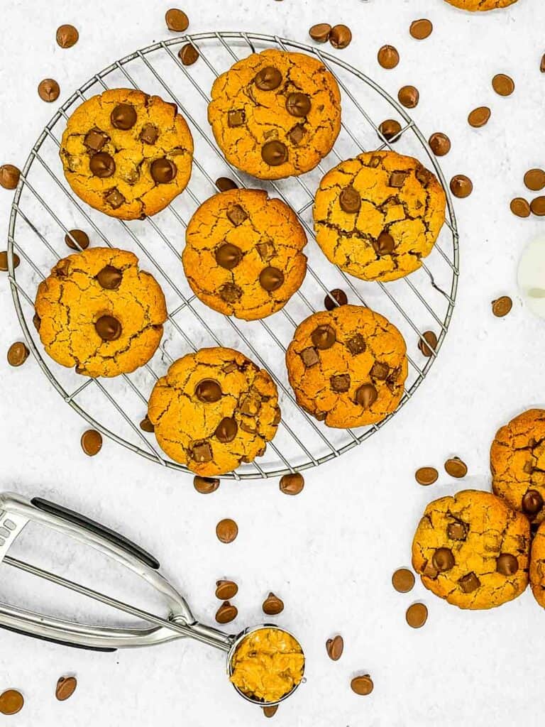 Air fryer peanut butter chocolate chip cookies cooling on a wire rack with a scoop full of cookie dough by the side.