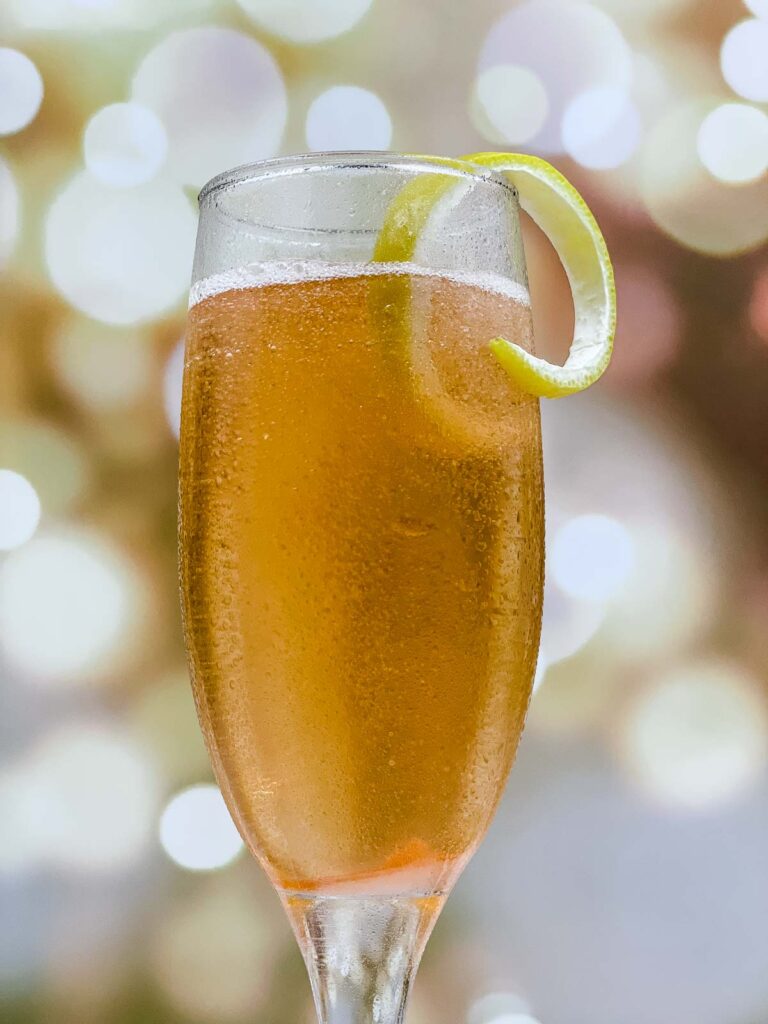 Closeup of a champagne cocktail with a lemon peel garnish.