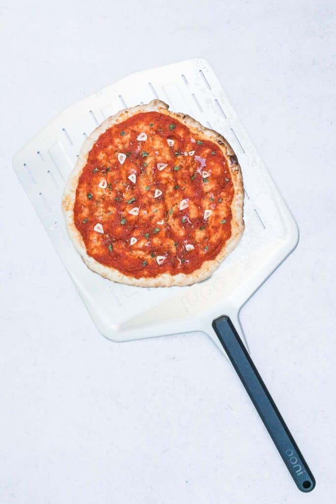 Cooked pizza marinara on a pizza peel.