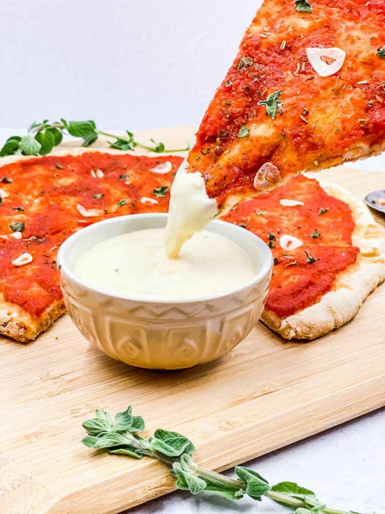 Dipping a slice of pizza marinara into some pizza dipping sauce.