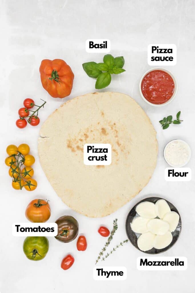 Ingredients needed, heirloom tomatoes, fresh bail, pizza sauce, flour, fresh mozzarella, fresh thyme, and pizza crust.
