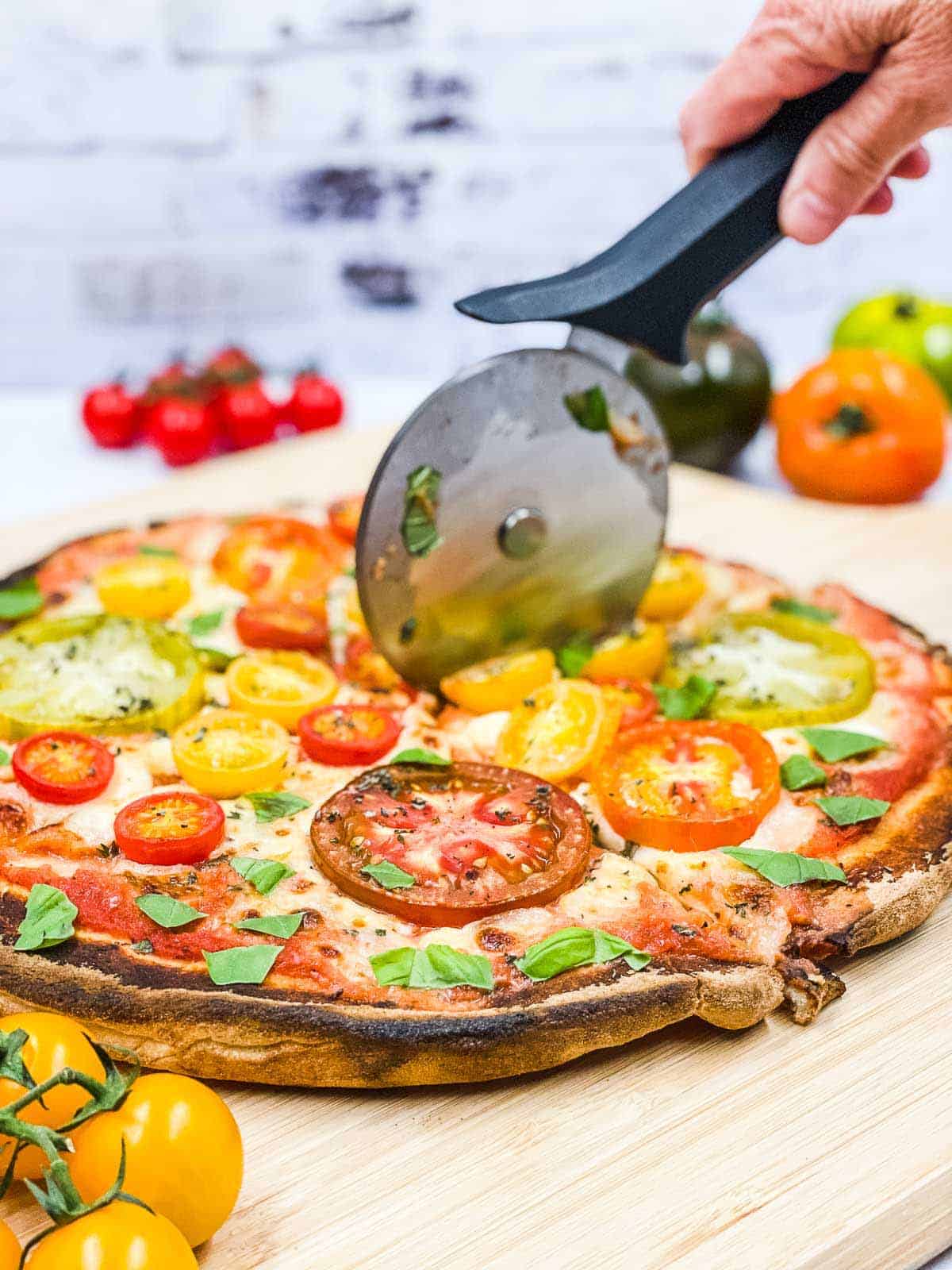 Someone using a pizza cutter to slice up pizza.