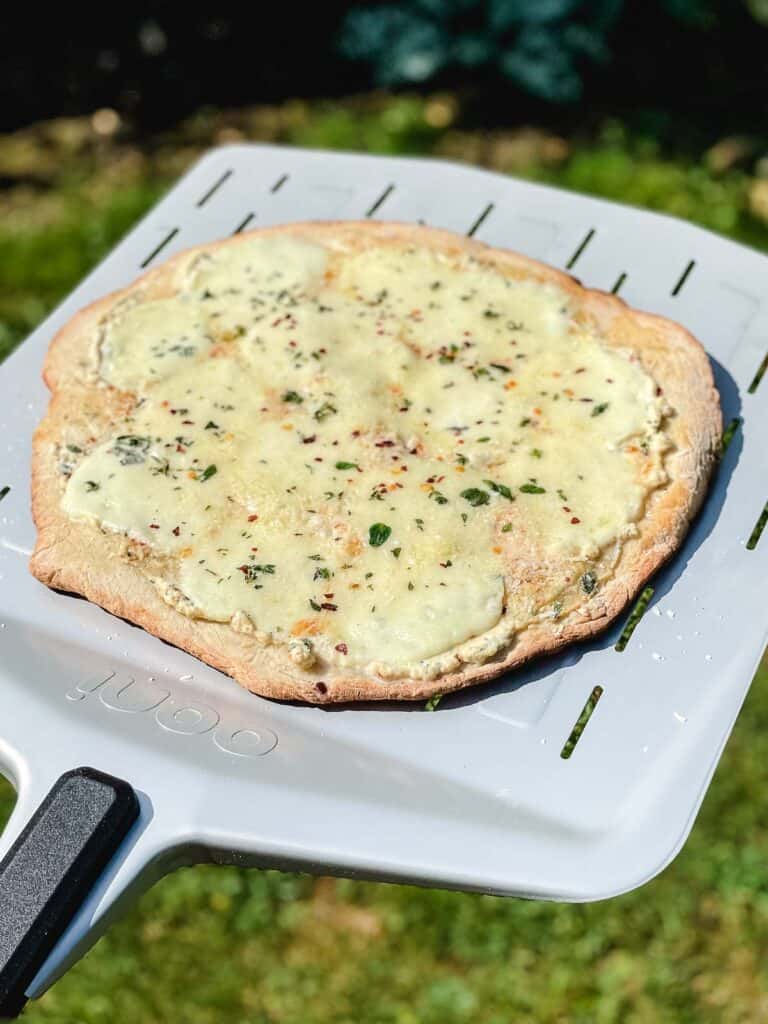 A freshly cooked white pizza on a pizza peel.