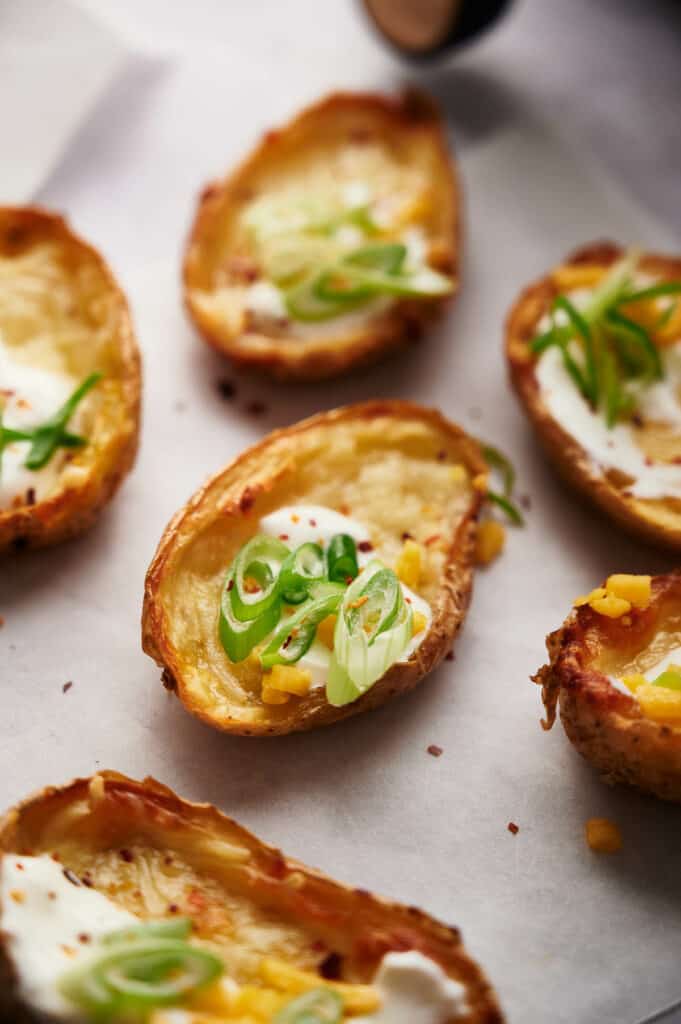 Air fryer potato skins freshly made with melted cheese, sour cream, and green onions.