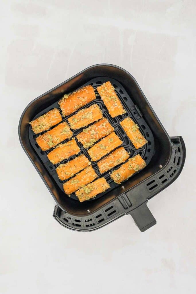 Carrots uncooked in an air fryer basket.