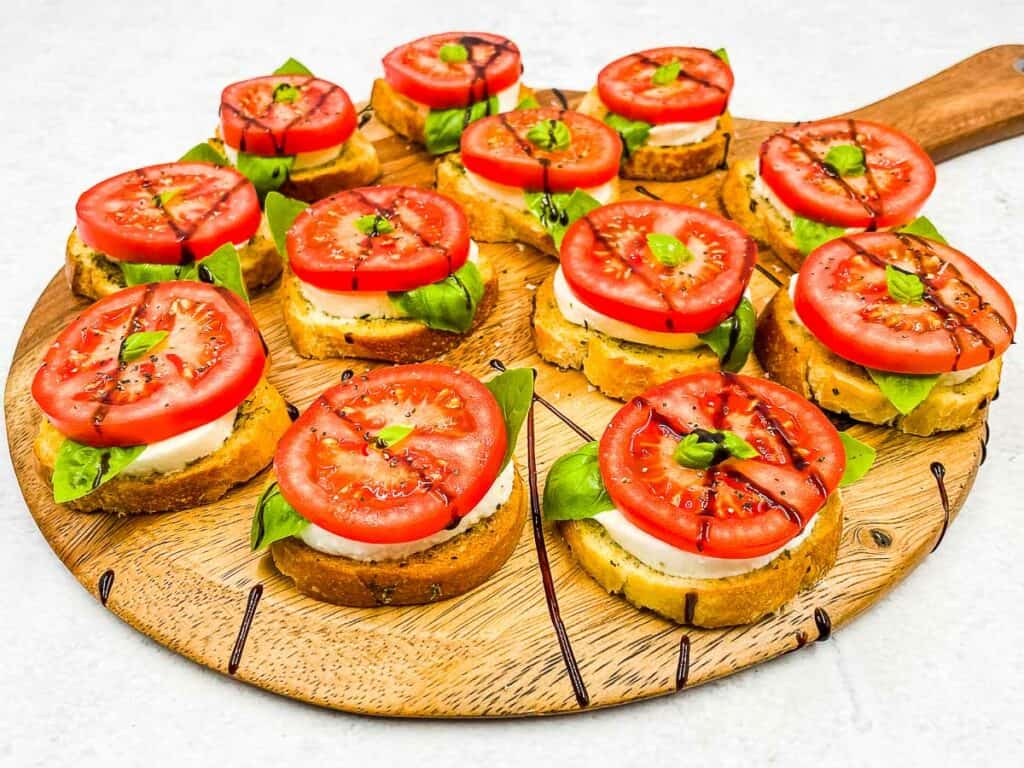 A serving board with Caprese appetizers, drizzled with balsamic glaze.