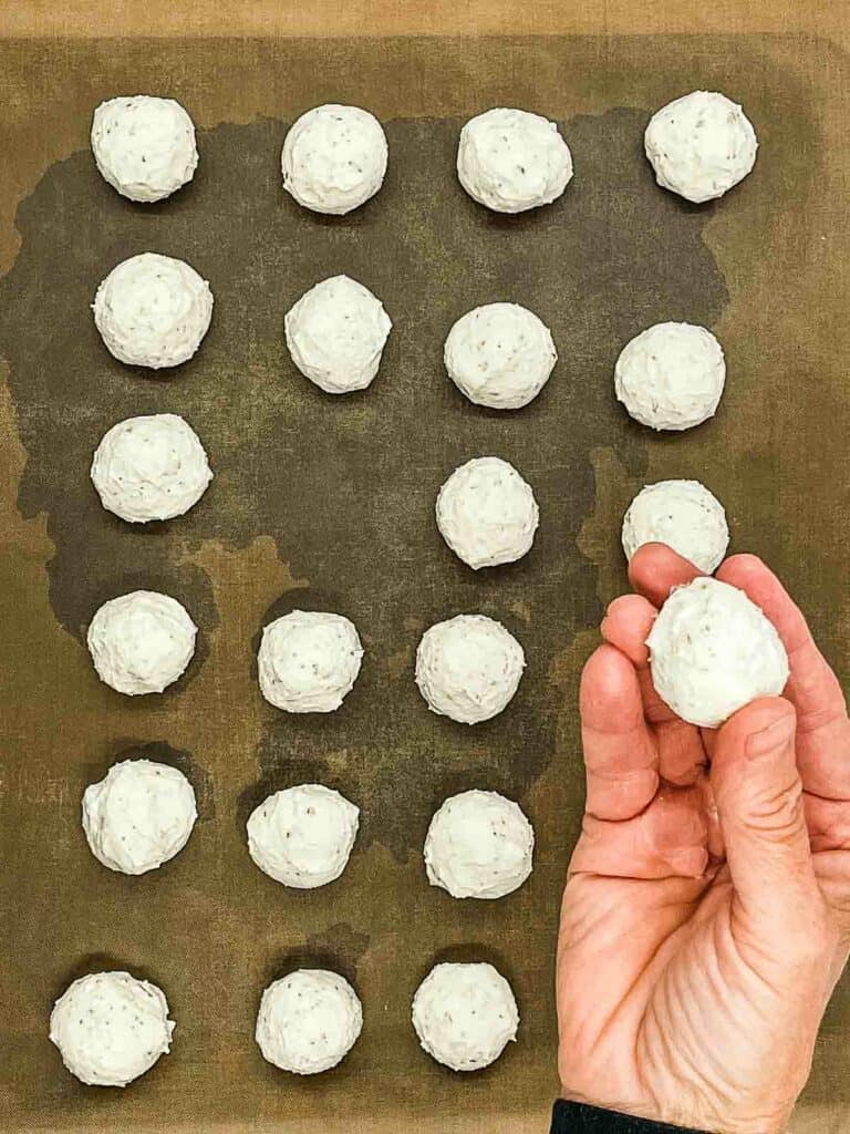 Someone shapping goat cheese into balls.