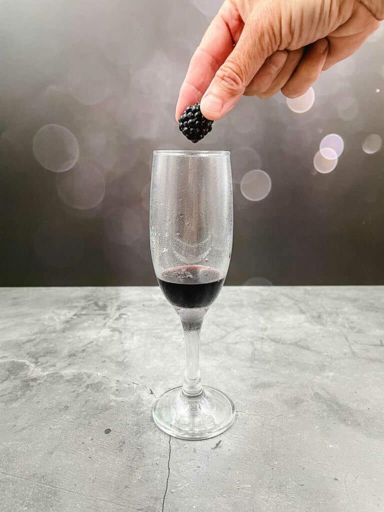 Placing a blackberry in a champagne flute.