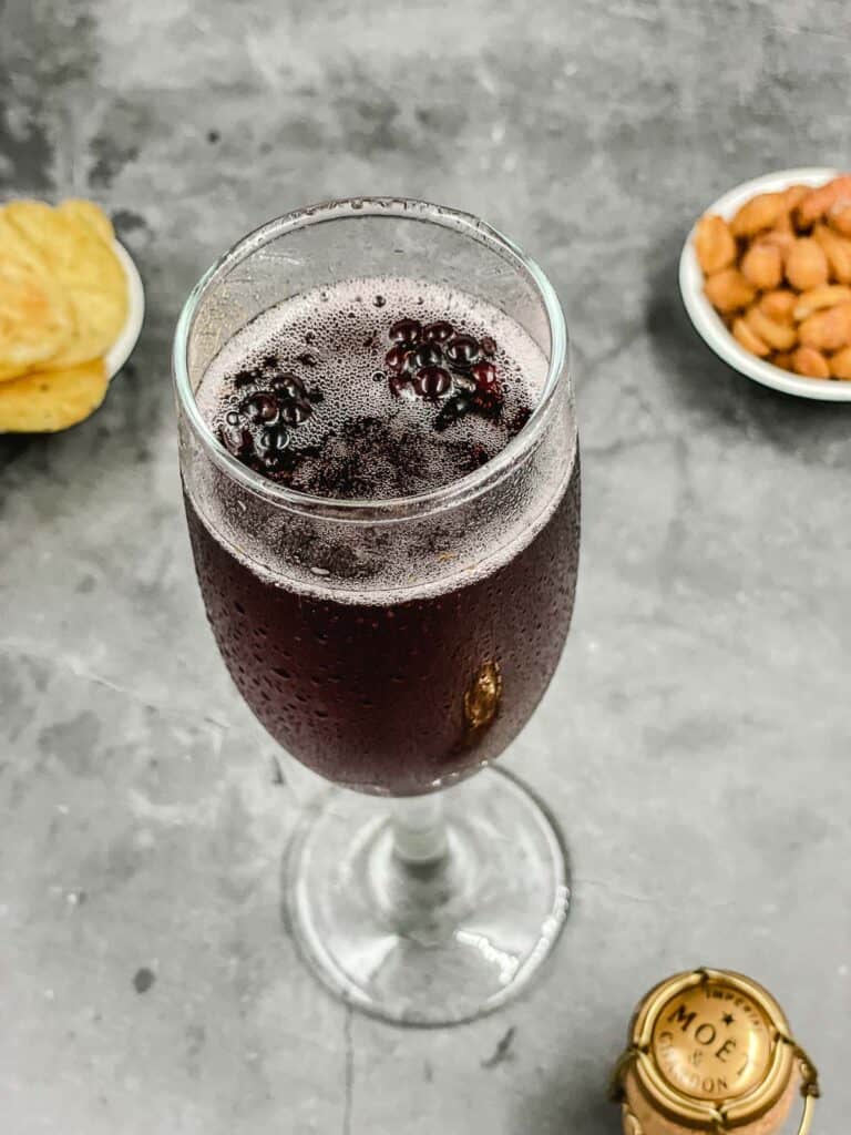 Blackberry floating on the surface of a champagne cocktail.