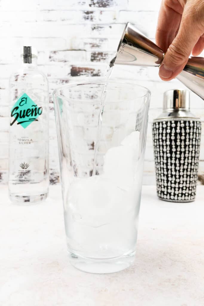 Adding ice, vodka and triple sec to a cocktail shaker.