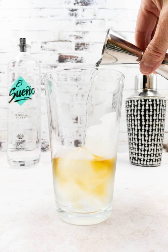 Adding rum, gin, and triple sec into a cocktail shaker.