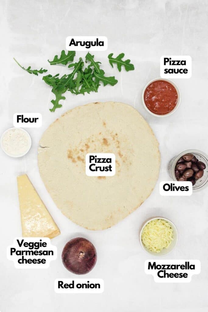 Ingredients needed, arugula, pizza sauce, olives. shredded mozzarella, red onion, veggie Parmesan cheese, flour, and pizza crust.