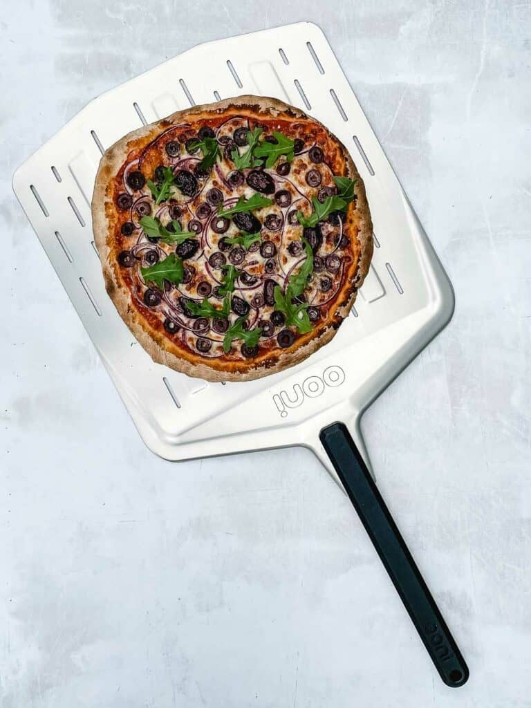 Cooked pizza on pizza peel.