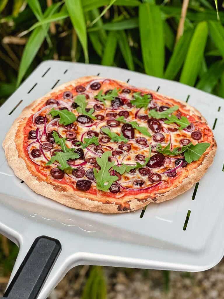 Straight out of the pizza oven olive pizza on a pizza peel.