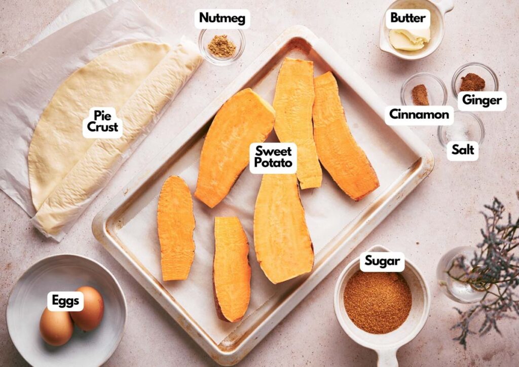 Ingredients for sweet potato pie are arranged on a table, alongside a plate of chocolate crinkle cookies, including sweet potatoes, pie crust, eggs, sugar, butter, nutmeg, cinnamon, ginger, and salt.