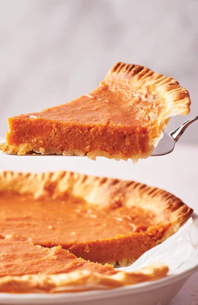 A slice of homemade sweet potato pie on a cake slice.