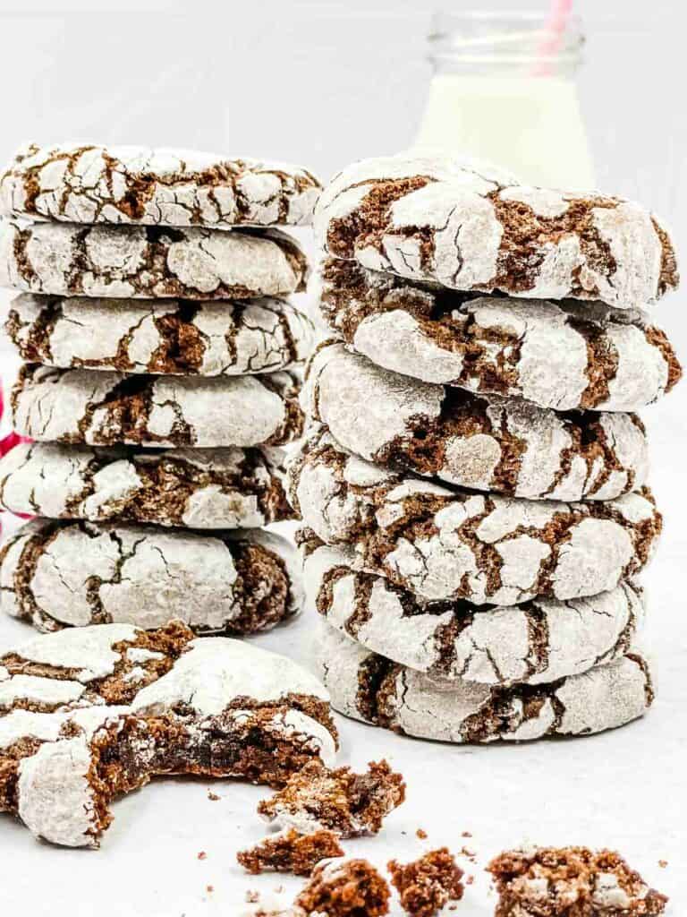 Chocolate crinkle cookies piled upon each other, one with a bite taken from it.