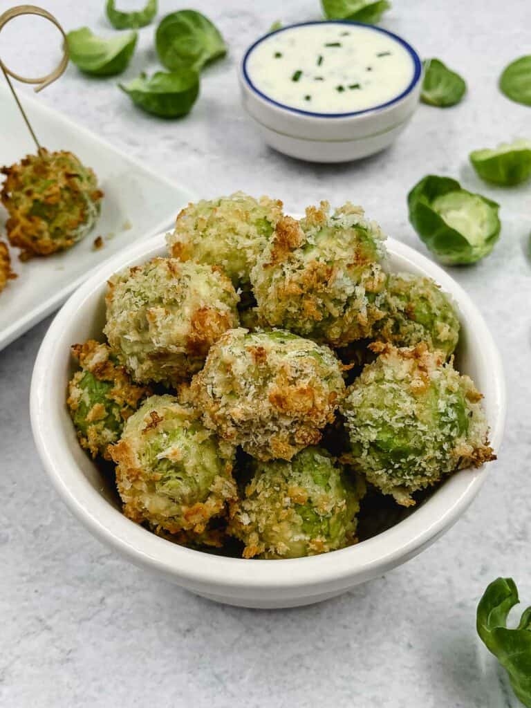 Cheesy Brussels sprouts bites with a bowl of sour cream behind.