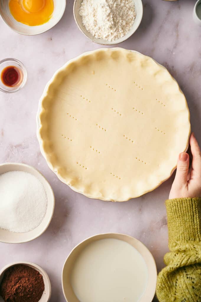 Someone holding a prepared pie crust.