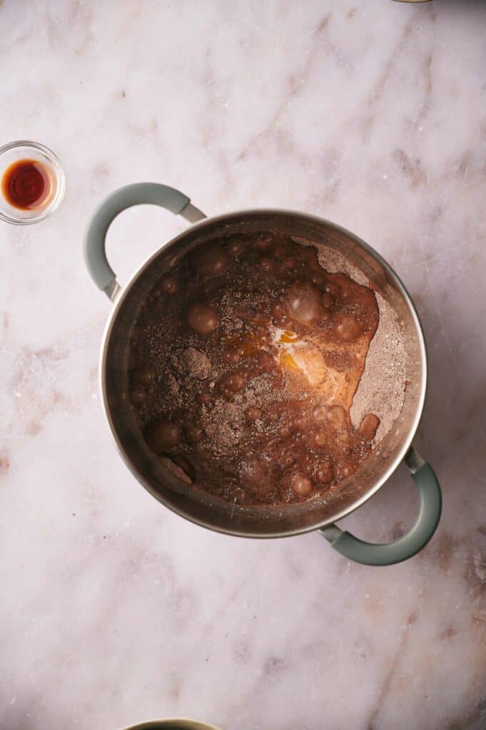 A pan with cocoa powder, salt, egg yolks, milk, sugar, and flour in.