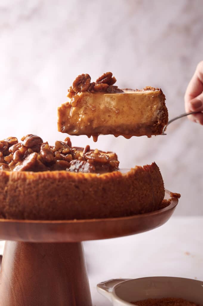 Someone helping themselves to a slice of pecan cheesecake.