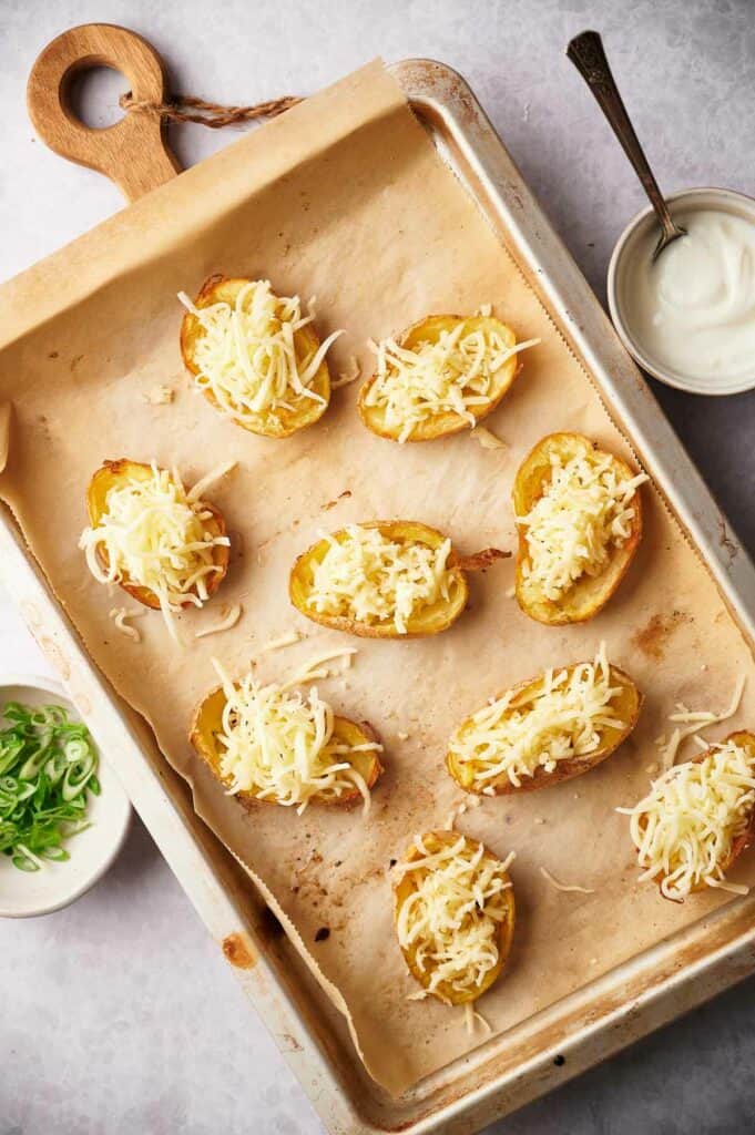 Potato skins with shredded cheese on them.