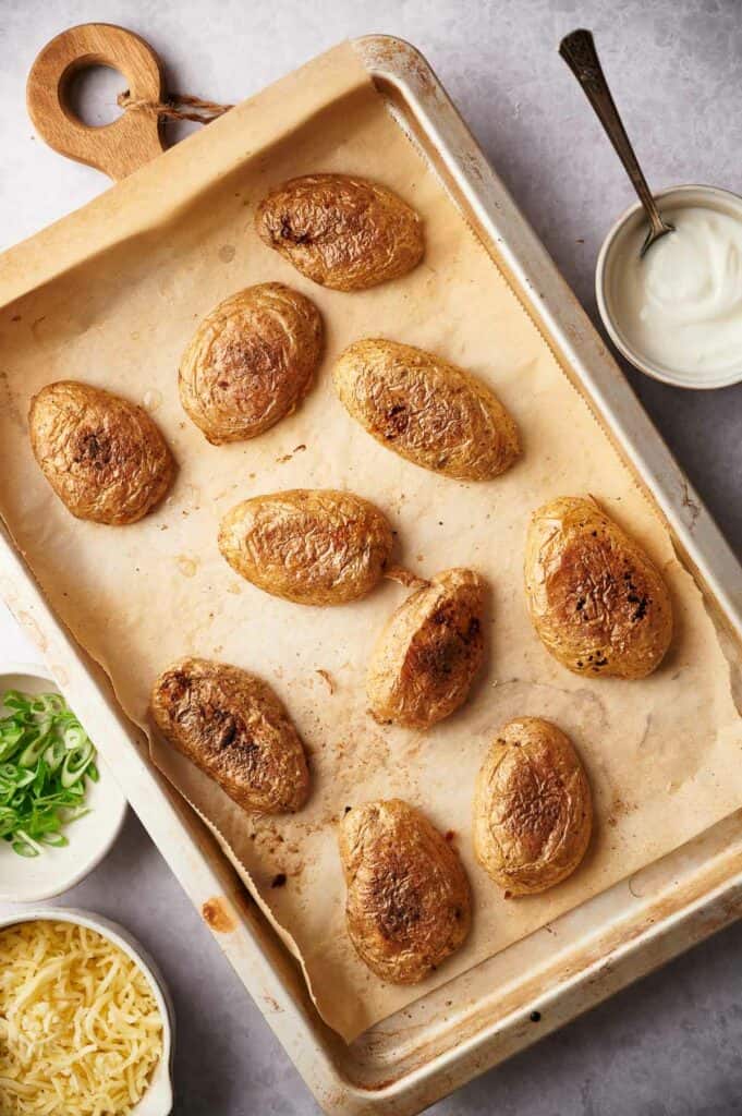 Baked potato skins cut side down on a baking sheet.