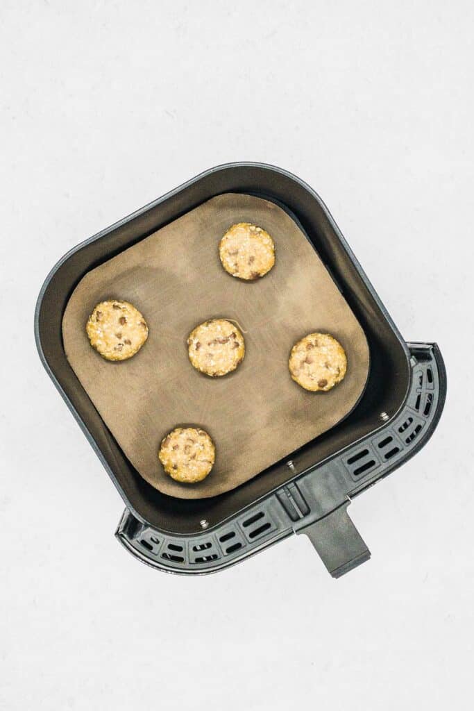 Cookie dough in air fryer basket on silicone parchment paper.