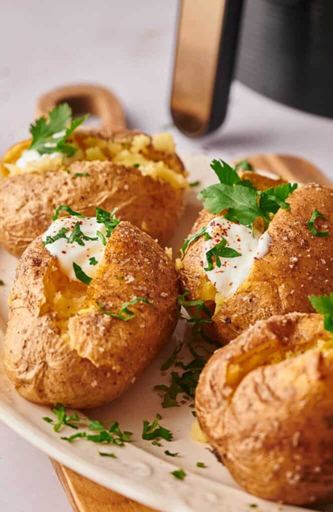 Air fryer baked potatoes, with sour cream and parsley loaded on them.