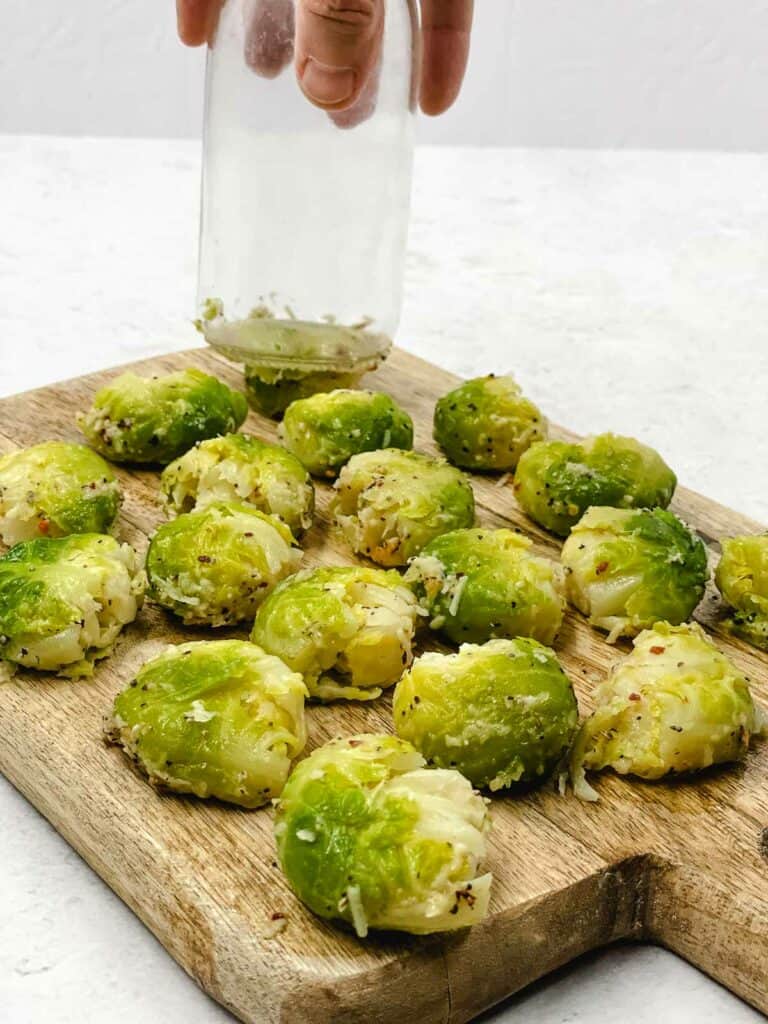 Someone smashing cooked Brussels srouts with a jar bottom.