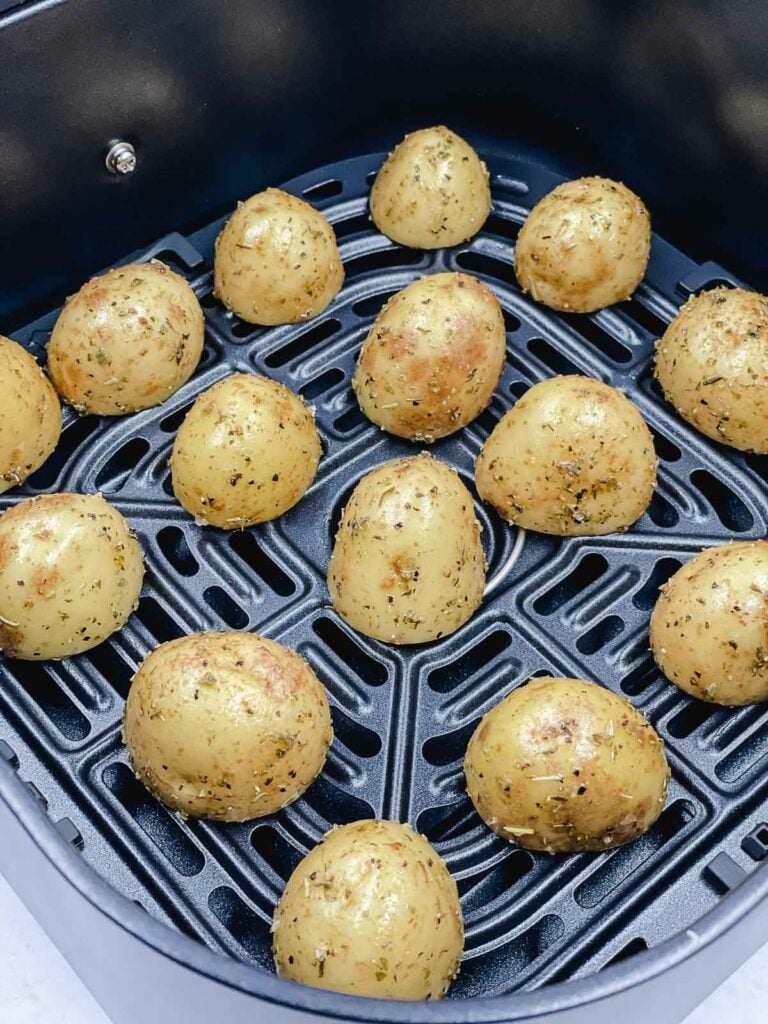 Baby potatoes cut side down in an air fryer basket, uncooked.