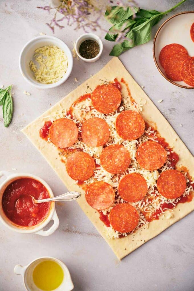 Vegetarian pepperoni slices on prepared pizza dough.