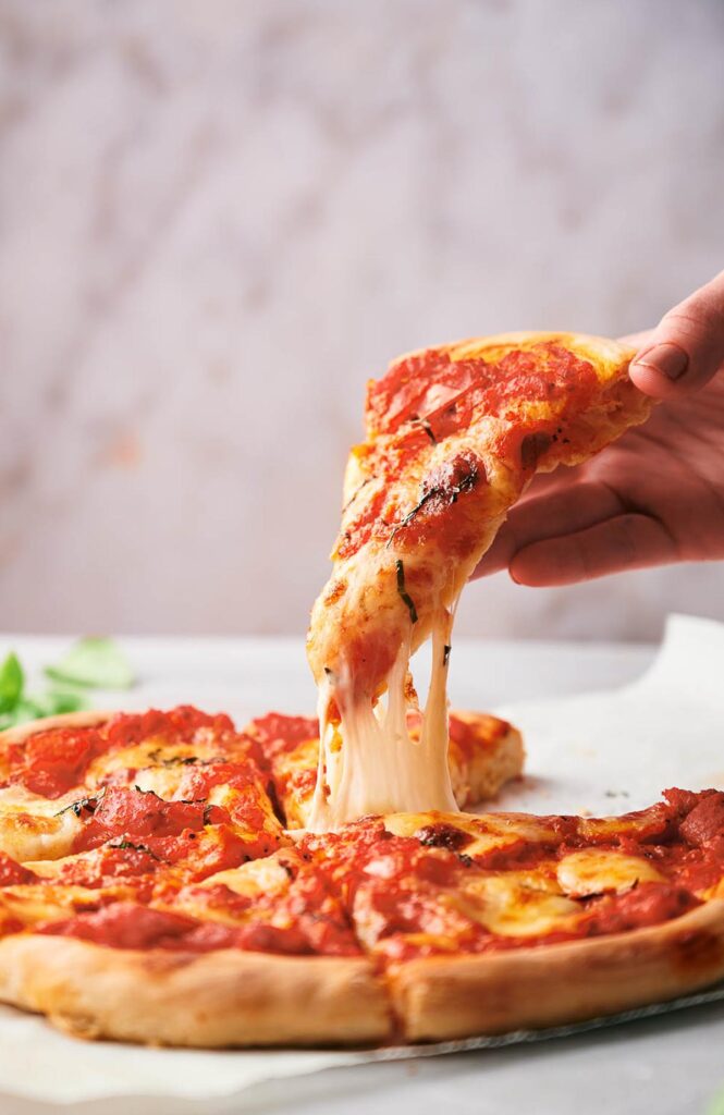 Someone helping themselves to a slice of Neapolitan pizza.