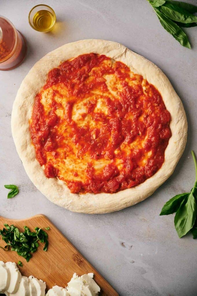 Pizza sauce spread on homemade pizza dough.