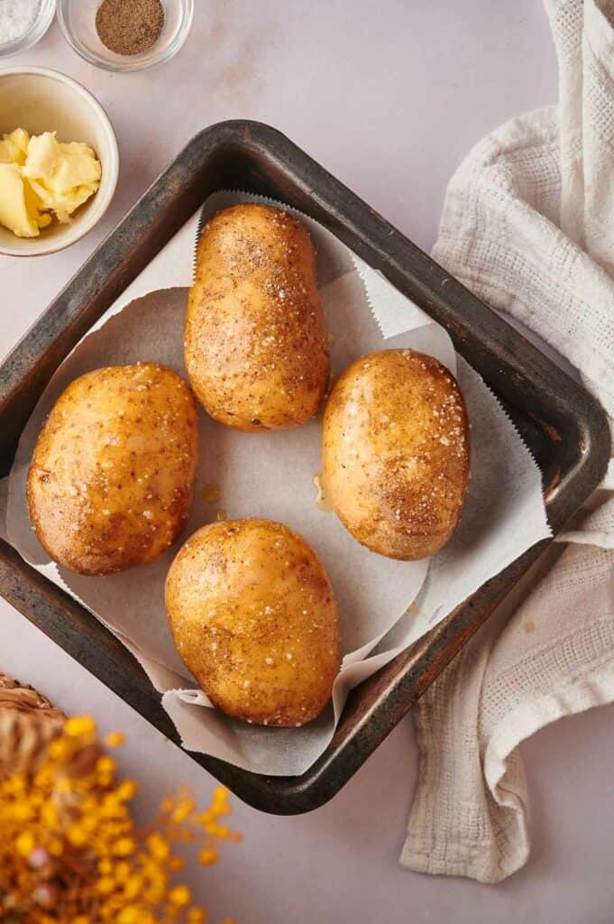 Baked potatoes uncooked on a baking sheet.