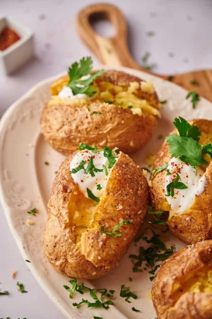Tasty freshly baked potatoes with fluffy insides and sour cream and parsley.