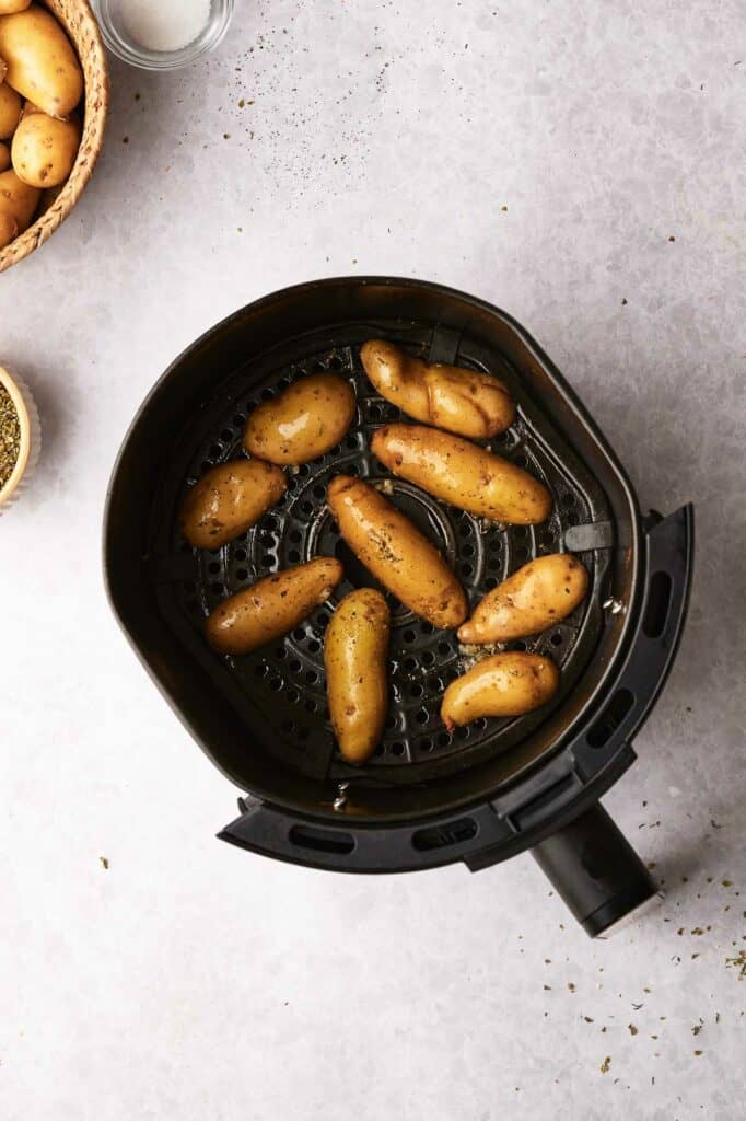 Uncooked fingerling potatoes in an air fryer basket.