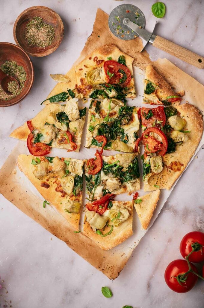 A delicious baby spinach pizza with artichoke hearts sliced and ready to eat.