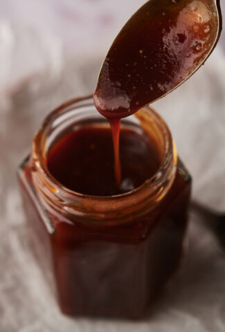 Homemade BBQ sauce with a spoon of it dripping into the jar.