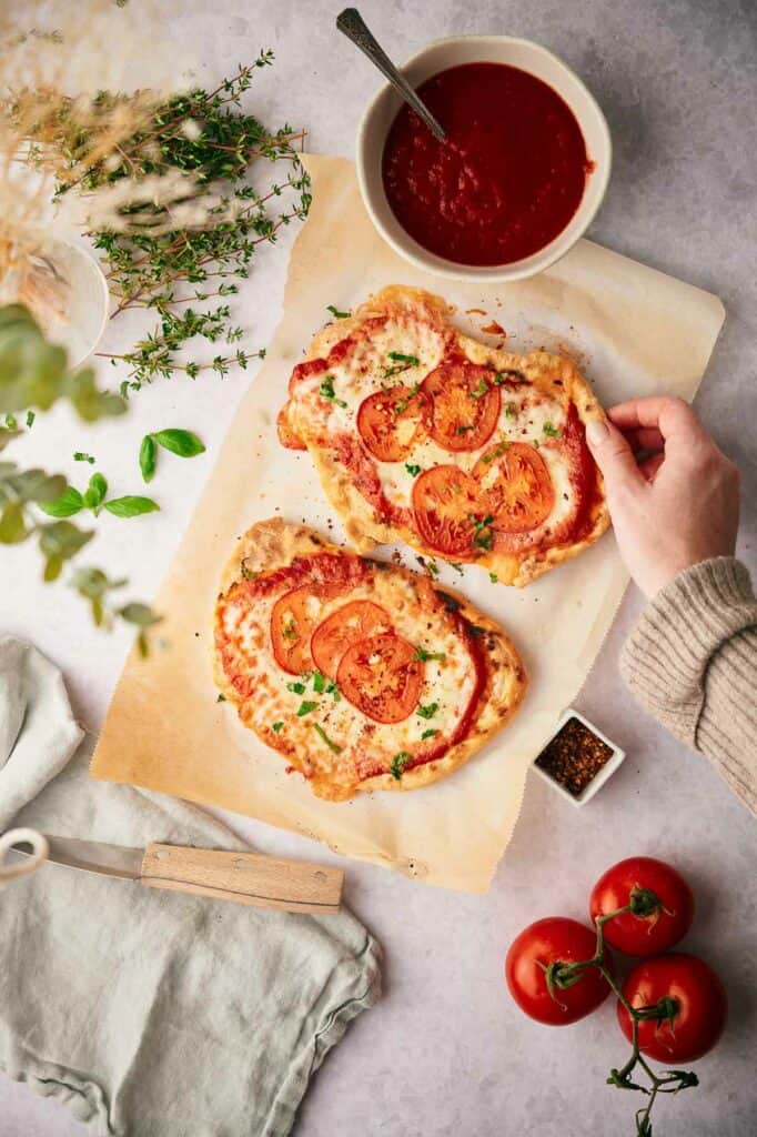 Someone picking up a cooked Margherita flatbread pizza.