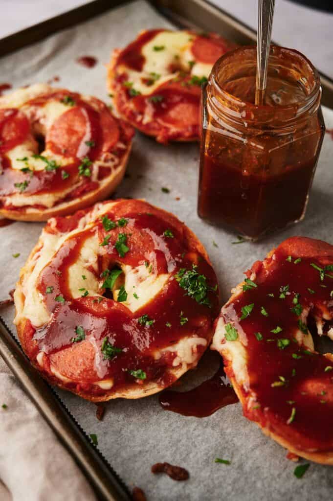 Pizza bagels cooked with BBQ sauce drizzled on them.