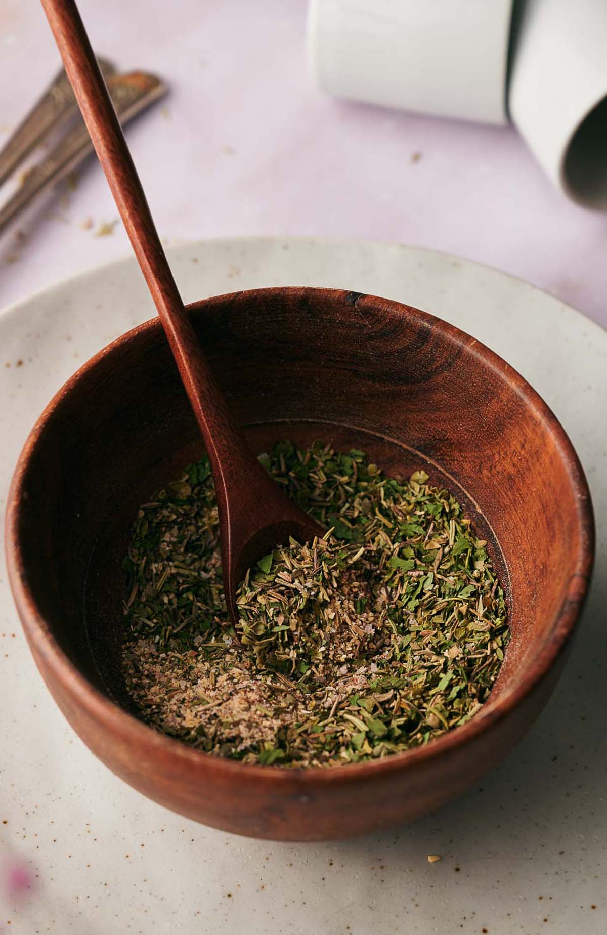Pizza seasoning mix in a wooden mixing bowl.
