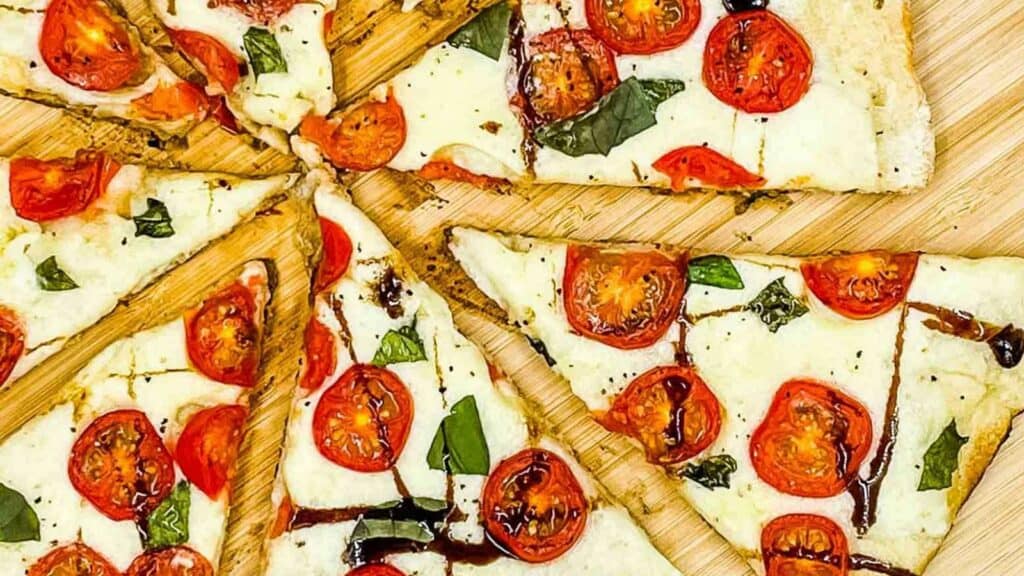 Caprese pizza with balsamic glaze drizzled over it.