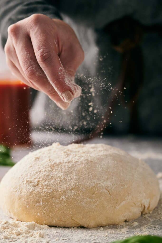 Someone coating Ooni pizza dough with flour.
